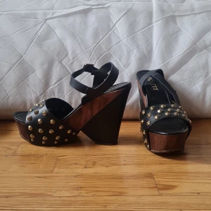 Klackskor  - Svarta skor med guldiga nitar och trä.