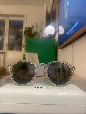 Sun Buddies Zinedine - Sun Buddies Zinedine Melted Butter   I gott skick.  Transparent vintage inspired biblio frame in a yellow tone, handmade of Italian acetate. Green Carl Zeiss lenses with 100% UV protection and a seven bar hinge with two visible rivets on the temple. 