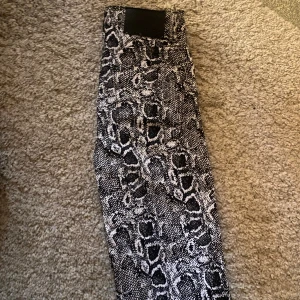 Ormskinns mönstrade jeans  - Jeans med ormskinns mönster från NA-KD. Storlek 34 men passar 32.  Mycket bra skick,testade men inte använda