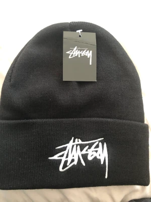 Stussy Mössa Svart - Testad på ett få tal gånger, 100% äkta medföljer original förpackning och så klart kvitto!  INGEN RETUR PÅ HUR DET PASSAR ELLER ÄKTEHETS FUNDERINGAR DÅ JAG HAR KVITTO