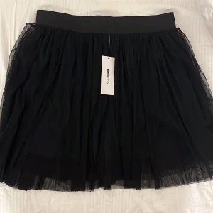 Svart kjol  - Säljer en oanvänd kjol ifrån Gina Tricot!! Kjolen är ungefär 40cm lång och i storlek M, tycker den skulle vara skit snyggt på mig om den vore i min storlek. Fick den som present utan kvitto så kunde tyvärr inte returera. Nypris 200kr! 🫶pris kan diskuteras
