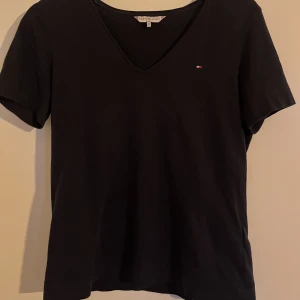 Tommy Hilfiger T-Shirt  - En marinblå lätt V-ringad T-Shirt från Tommy Hilfiger som fortfarande är i fint skick och inte använd på några år. 