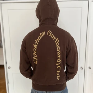 Stockholm Surfboard Club Hoodie  - Säljer denna Stockholm Surfboard Club Hoodie då den är för liten och inte används. Jag är 183 cm och bär storlek S på bilden. Den är använd men ändå i väldigt bra skick! Inga hål eller slitningar! Nypris 3000 kr😁