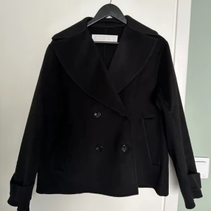 ARKET kort kappa - ARKET kort kappa Storlek 38 Färg: Svart Skick: som ny, använd en gång Material: 80% ull, 20% polyester Nypris: 2590 kr, mitt pris 1479 kr inklusive fraktkostnader (slutsåld på arket.com) Samma som på länken: https://www.arket.com/sv_se/women/jackets-coats