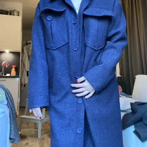 Blå kappa - Från NAKD! Använd men i fint skick. Marinblå men uppfattas något ljusare på bilden. Jag är 160cm och kappan går till mina knän i storlek 34. 