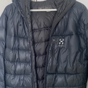 Hagalöfs vinterjacka man  - Vinterjacka i strl L i haglaöfs för män , kedjan är lite sönder men är enkelt att fixa , går att mötas upp eller frakta men fraktavgift medföljer.