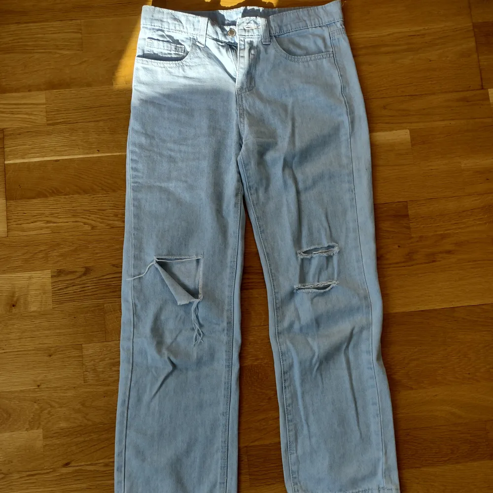 Ljusblå jeansbyxor som har hål i sig och är lite baggy.. Jeans & Byxor.