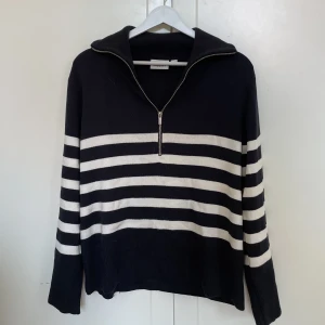 Blå vit randig kofta - Randig stickad tröja med krage och ribbad mudd i ärmslut samt nertill. Tröjan har dragkedja i kragen och en lång lite vidare ärm. Rak modell i en löst sittande passform. Använd runt 3 gånger. Kvaliteten är som nyköpt.  Org pris- 499kr