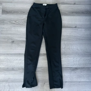 Svarta kostymbyxor  - Svarta kostymbyxor från NAKD. Med en slit nere vid benet. Storlek 34. Väldigt stretchiga och bekväma. 