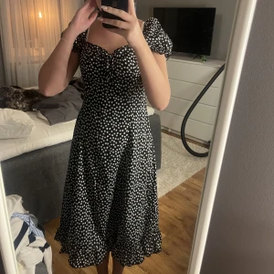 Blommig klänning - Svart klänning med vita blommor på. Puffärmar och knyt vid bröstet. Aldrig använd. Köparen står för frakten💗💗