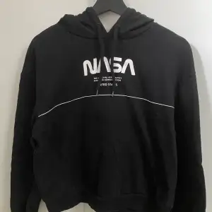 En nasa hoodie från hm med luva och text på ryggen.