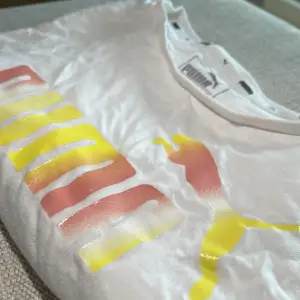 T-shirt i kort modell med glansigt färgglatt tryck på bröstet. Bra skick, endast använd ett fåtal gånger. 