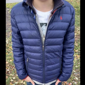 Ralph Lauren jacka - Fin Ralph Lauren jacka i använt skick, de stora defekterna ser du på bild 3. Då det är ihopsytt över ena fickan och några småhål under vänster arm. Modellen på bilden är 155cm lång. bild 1 utspelar färgen bäst.