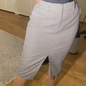 Svartvit Tommy Hilfiger kjol - Långkjol med slits framtill. Materialet är tjockt och finns även en insydd underkjol som gör att man kan anvönda den vintertid. Vackert mönster.