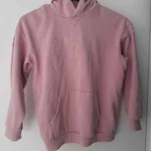 Rosa Hoodie Storlek 134/140 H&M - Rosa Hoodie Storlek 134/140 H&M  Strass text i rose guld sams lila tryck på ärmarna med texten NYC  Obs, hund finns i hemmet   Fraktas enligt överenskommelse. Frakten bekostas av köparen.  3 för 2 på alla Hoodies/Tröjor   PRISET GÅR ATT FÖRHANDLA