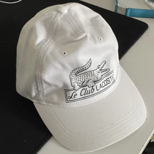 Lacoste keps - Skön keps aldrig använd, adjustable strap där bak och sitter ish som en baseball cap. Bara provad, nypris 650