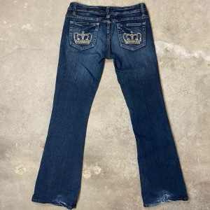 Lågmidjade Jeans   - I okej skick, flera kristaller har ramlat av. Slitmärken med hål längst ner. 5% stretch. Påminner om Victoria Beckham jeans. ⚠️Mått: Höft 41cm, grendjup 20cm & innerbenslängd 84cm. 