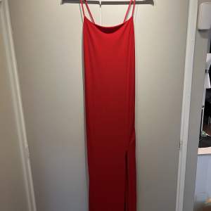 Lång, röd klänning med slits. Stl 38 Material: bomull Aldrig använd.