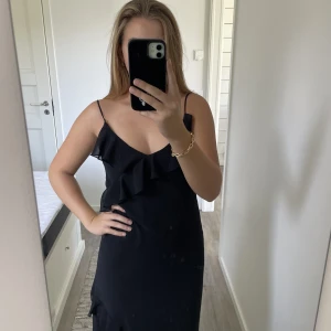 Svart långklänning - Säljer denna svarta långklänning med volanger! Perfekt till bal eller liknande. Öppen i ryggen. I nyckick💕