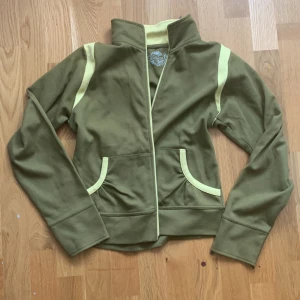 Grön y2k zip-up - Jättefin & mjuk grön zip-up med gula detaljer och tryck på ryggen💝står ingen storlek men passar xs-m beroende på hur man vill ha passformen. Har några lösa trådar vid ena axeln (se sista bilden) men är annars i bra skick. Märket heter Masita💖
