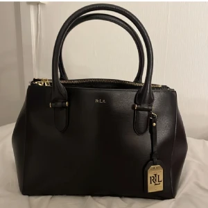 Ralph lauren väska  - Jätte fin vintage väska från Ralph lauren. Väldigt smidig med flera fack. Nypris 2995kr.   Finns några repor på guldbrickan men inget man lägger märke till