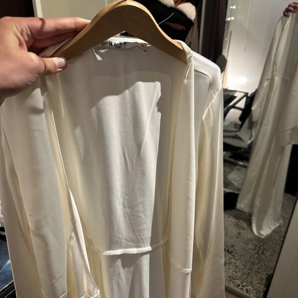 Nakd vit lång omlottklännings i så fint tyg. Helt oanvänd, köptes till studenten men användes aldrig:). Nypris 700 kr. Storlek 42. . Klänningar.