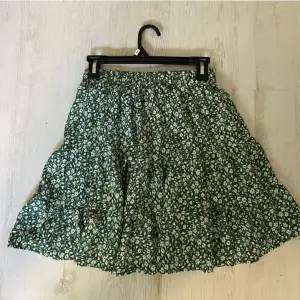 Superfin blommig kjol i grön färg. Strl M men resåren i midjan gör att det kan passa både större å mindre storlekar.