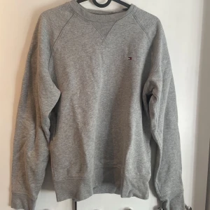 Tommy Hilfiger crewneck - Säljer en grå Tommy Hilfiger crewneck tröja. Inga fläckar bara lite skrynklig. Kan säljas för ett lågt pris.