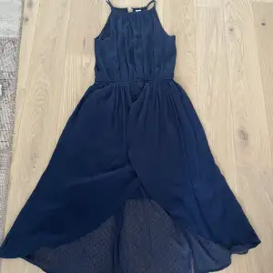 En mörkblå klänning i jätte bra skick med fantastiskt fin nederdel som har lite lättare tyg som fladdrar i vinden.