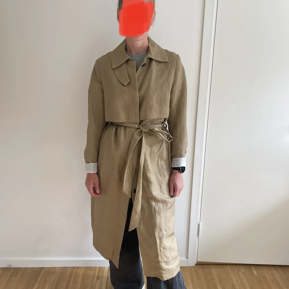 Jättehärlig trenchcoat i nyskick som förtjänar mer än att bara hänga i min garderob. Använd ett fåtal ggr. Inga defekter. Normal i storlek. Nypris 1799:- Material: 60% linne 40% viskos. Jackor.