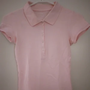 Ljusrosa pikétröja / kortärmad topp. Bomull. XS. LOGG. - Ljusrosa pikétröja / kortärmad topp. Bomull. XS. LOGG. Liten defekt/ svag missfärgning längst ned på ena sidan. Är dock endast från mörkt plagg som legat på plagget och går troligen bort i vanlig tvätt. Se bild 3.