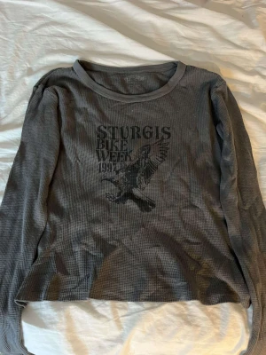 Tröja - (ALDRIG ANDVÄNT) Grå tröja med svart tryck, står ingen storlek men passar som xs-s. Kan inte läsa vilket märke det är.