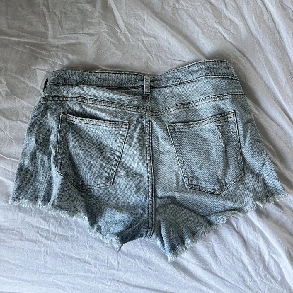 Ljusblå jeansshorts med slitningar! I mycket bra skick. Märket på jeansshortsen samt storleken har försvunnit men skulle uppskatta att det är en XS.. Shorts.