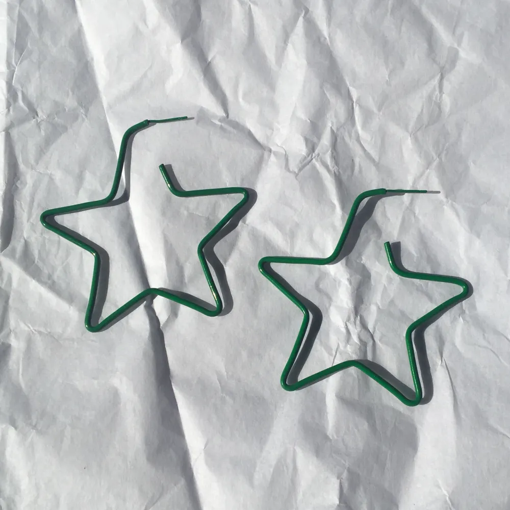 Gröna stjärnformade örhängen i okänd metall. Bra skick, dock är piggen något sned på ena. . Övrigt.