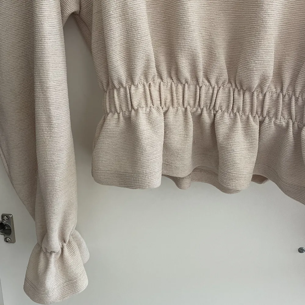 En beige tröja från Gina tricot med fina detaljer runt midjan och handlederna! I storlek xs❣️. Toppar.