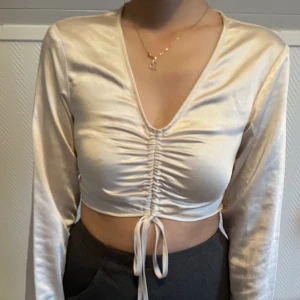 Croptop från NAKD - Har använt denna söta champagne färgade toppen endast en gång och säljer då den inte längre passar. Storlek 34 och orginal priset var 399 kr