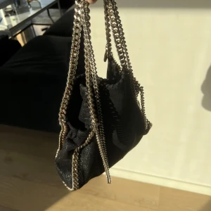 STELLA MCCARTNEY FALABELLA - Säljer min superfina Falabella Stella Mccartney väska i storleken medium. Svart med guldig kedja!