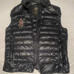 Morris väst  - Morris väst. Storlek: Large ( passar för de som har M )  perfekt för hösten och början på vintern. Perfekt att ha på sig med en jacka över men även perfekt att ha på sig västen i sig själv. Vind tät. Är i bra skick 