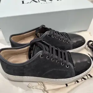 Lanvin (mörk grå)  Patent Cap Toe Sneaker Dark Grey. Storlek 40,  UK6 (stor i storleken) Skick 10/10. Alla tillbehör som Kartong, skosnören, skopåsar finns. Oanvända , självklart original, kvitto finns! 