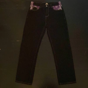 Coola y2k jeans med lila print - Feta svarta jeans med lila print där det står ”devil”. Det är storlek M och den ända defekten är att botten av jeansen är pytte lite ripors då jag har går med de så de har slits. Pris kan diskuteras