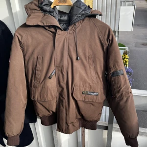 Brun dunjacka. *Canada Goose* - Brun dunjacka. Själv köpt på second hand så kan ej intryck äktheten på jackan och märket Canada Goose. Passa en storlek XS, S och kanske M. Går bra att buda.