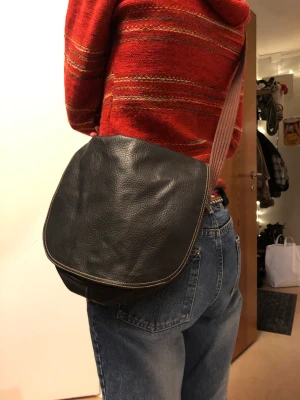 Axelremsväska - Brun axelremsväska i skin. Dragkedjan är trasig, men den går att stänga med magnet knapp. Skriv för mått! Har även en ficka med dragkedja på baksidan 