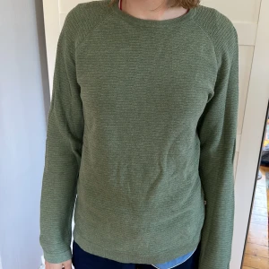 Grön långärmad tröja  - Tröja i märket East West i 100% bomull. Aldrig använd utan defekter, som ny.  Gjord för män men passar lika bra på vem som helst, som syns på bilden. Kan mötas upp i Eslöv eller Lund, annars står köparen för frakt.