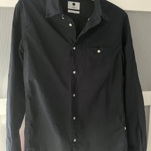 NN07 skjorta - Marinblå slimfit skjorta från NN07. Köpt från NN07 sektion i Åhléns för ca 3-4 år sedan. Använd men absolut inget som syns. 