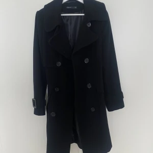 Kappa - Svart kappa. Sparsamt använd väldigt fint skick. Knytning runt eller bak. Storlek 36/38 står det i den, men mer som en 38.