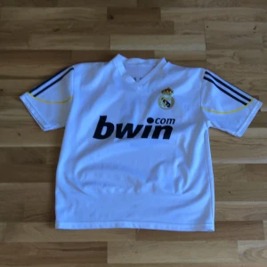 Retro Real Madrid home-kit - Denna tröja har följt med i hela 2 generationer och är i jätte bra skick denna tröja vet jag inte vad min pappa har köpt den till min store bror som har också haft den denna tröja är från när Cristiano Ronaldo spela med nr.9 i Real Madrid