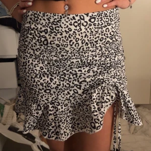 Kort kjol - Snörning vid ena benat. Har en dragkedja baktill. 