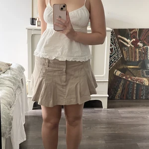 Minikjol - Beige plisserad minikjol. Sitter lågt på höfterna.