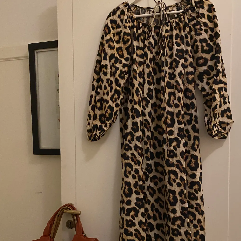 Klänning med leopardmönster från H&M. Loose fit med tillhörande snöre som går att knyta runt midjan för att få  mer figur på klänningen.  Knappt använd, mycket gott skick.  Stor i storleken dock något tight i resåren på ärmarna. Passar även en ”M”. Klänningar.
