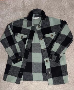 Grön & svart rutig ytter skorta - En skön, oversized skorta gjord på yttertyg och polyester. Köpt på hm 2022-2021, lätt använd.